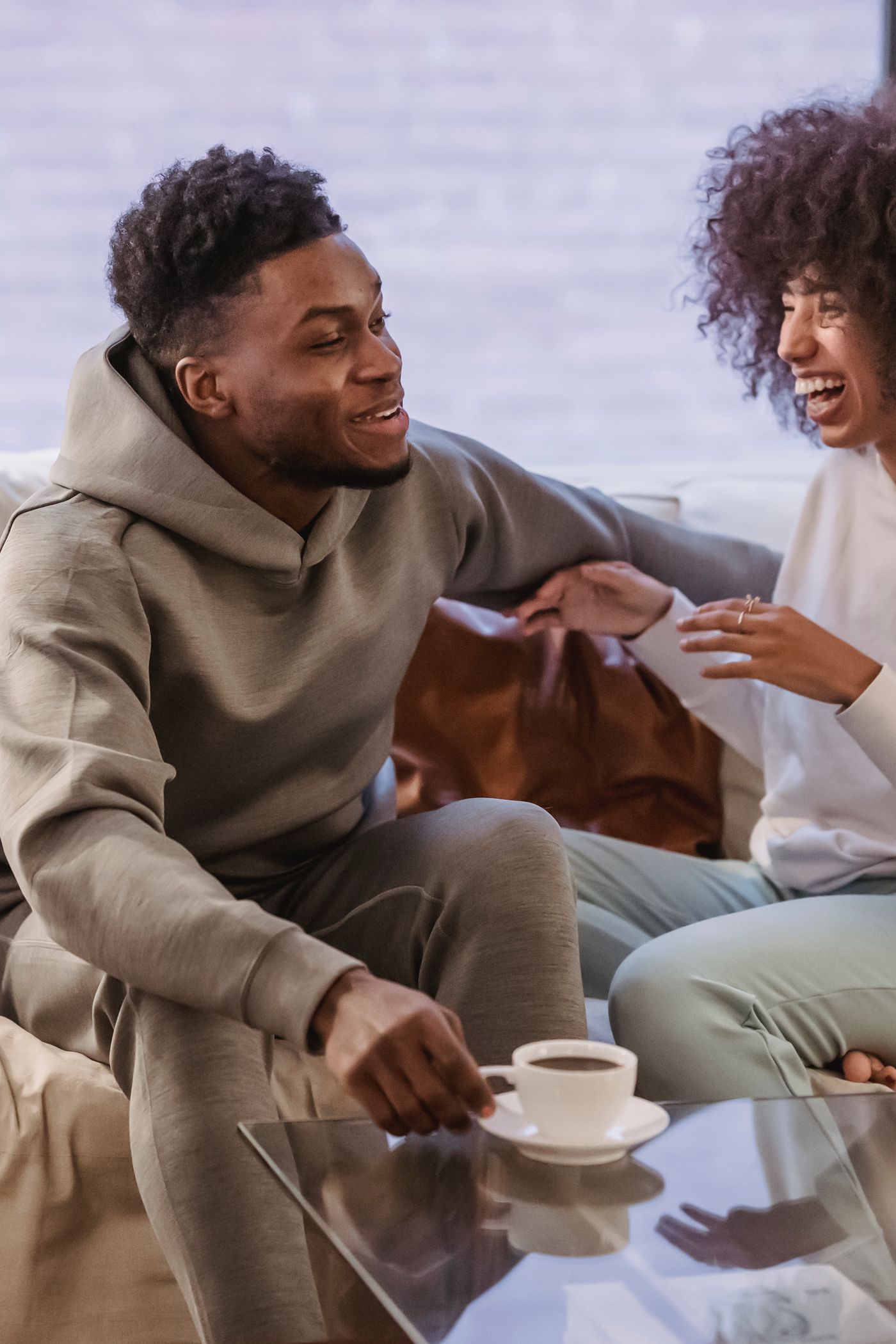 A couple laughing together at home over coffee